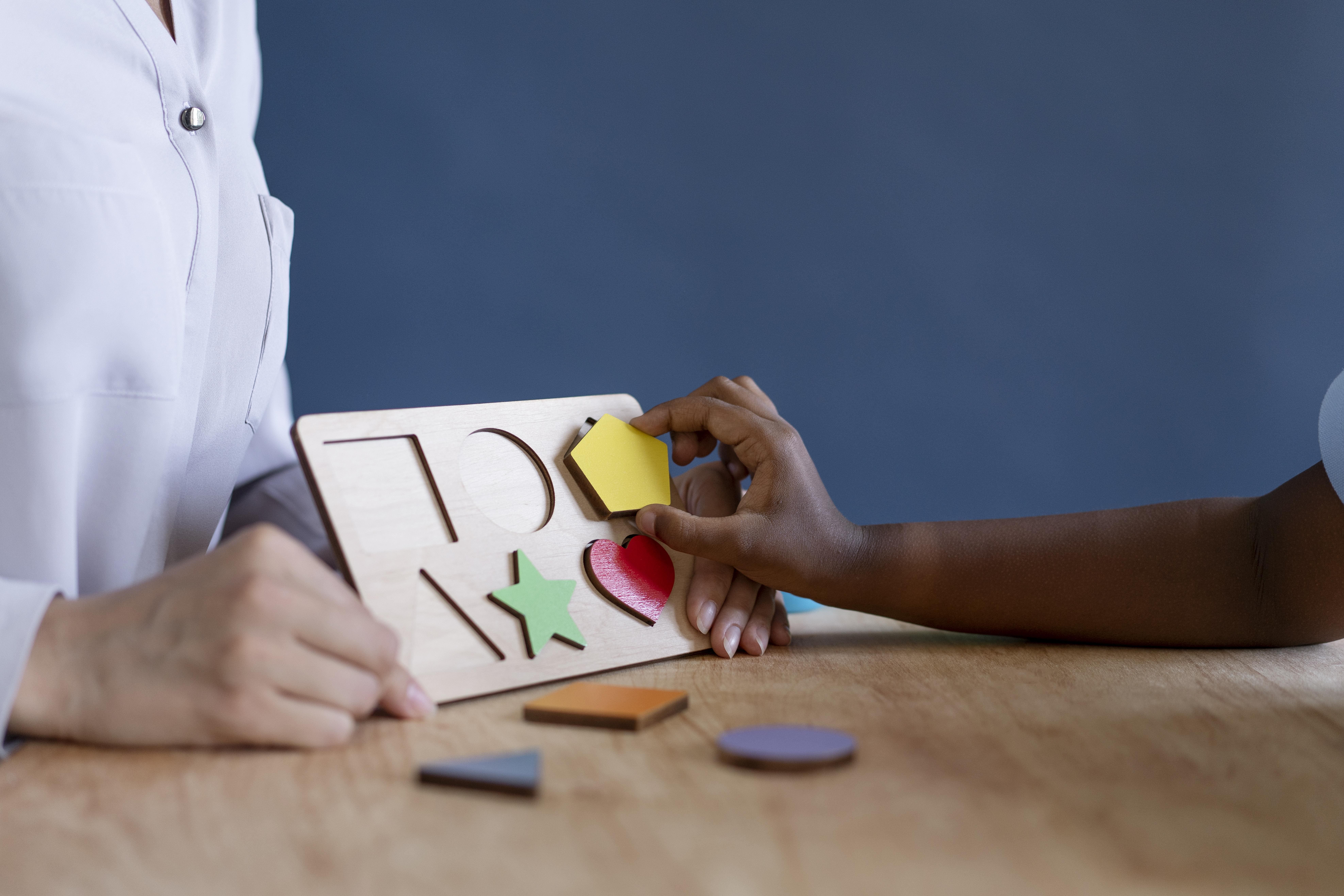 Criança em sessão de terapia multidisciplinar com profissional de saúde, ilustrando tratamento de transtorno do espectro autista